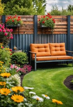 a couch sitting in the middle of a lush green yard next to flowers and trees