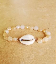 a shell and beaded bracelet on a table