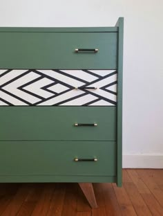 a green dresser with black and white lines painted on the front, two brass pulls at the bottom