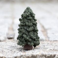 a small crocheted pine tree sitting on top of a stone slab