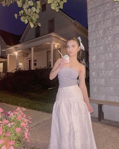 a woman in a white dress is holding a cell phone and looking at the camera