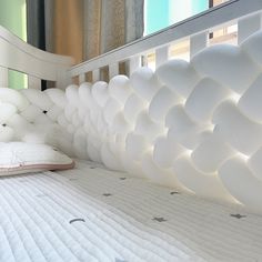 a white bed with pillows on top of it and a pillow under the headboard