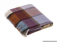 a multicolored plaid blanket folded on top of each other with fringes around the edges