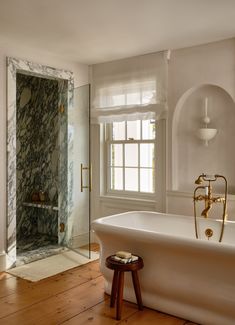 a white bath tub sitting in a bathroom next to a window