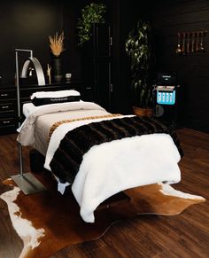 a bed with white and black blankets in a room next to a plant on the floor