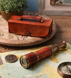 an old fashioned telescope sitting on top of a table next to a map and compass