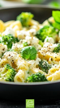 broccoli and cauliflower pasta in a skillet with basil leaves on top