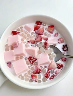 a bowl filled with milk and strawberries next to a spoon