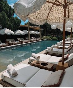 an outdoor pool with lounge chairs and umbrellas