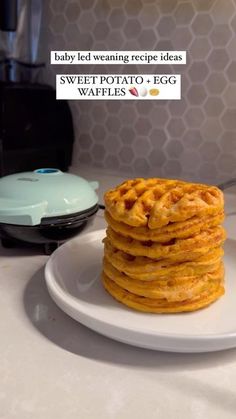 a stack of waffles sitting on top of a white plate next to a toaster