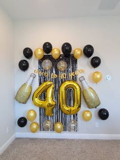 balloons and streamers are arranged in the shape of a number forty with black and gold balloons