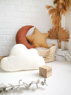 a white table topped with pillows next to a basket filled with leaves and branches on top of it