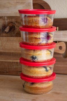 four plastic containers stacked on top of each other filled with blueberries and muffins