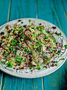 a white plate topped with salad on top of a wooden table