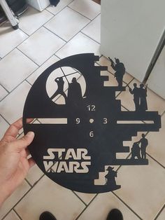 someone holding up a star wars clock on the floor