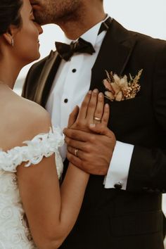 a bride and groom kissing each other in front of the ocean on their wedding day