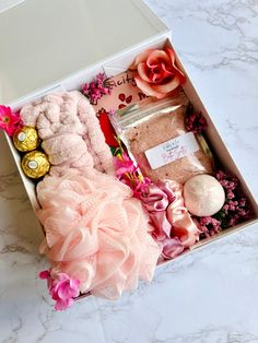 a box filled with lots of different items on top of a white countertop next to a pink flower