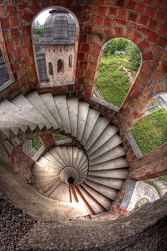 an aerial view of a spiral staircase in a brick building with arched windows and a clock tower