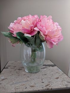 pink flowers in a clear glass vase on a marble table