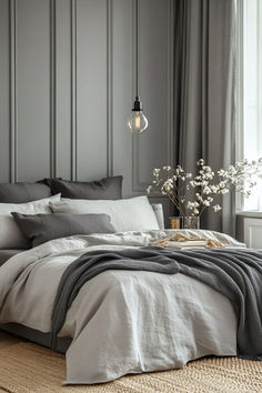 a bedroom with gray walls and white linens on the bed, along with a vase filled with baby's breath flowers