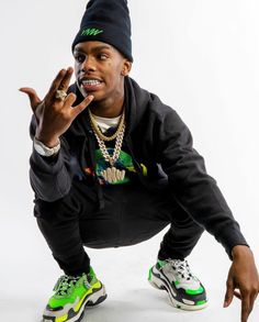 a young man is posing with his hands in the air while wearing green and black sneakers