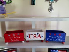 three wooden boxes painted with the colors of the american flag on them, sitting on top of a shelf