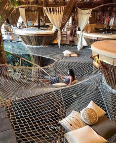 a woman laying on top of a hammock in a room filled with lots of pillows