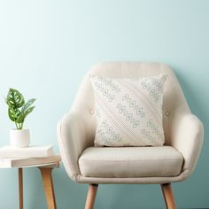 a chair with a pillow on it next to a potted plant