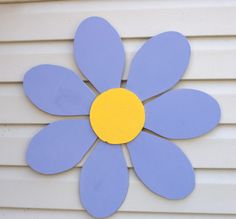 a blue and yellow flower sitting on top of a white wall next to a building