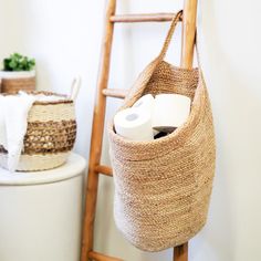 two rolls of toilet paper sitting in a basket next to a ladder