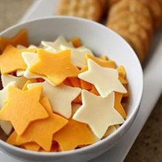 a white bowl filled with cheese and star shaped cookies next to crackers on a table