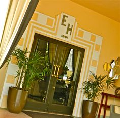 two potted plants sit in front of the entrance to an apartment building that is decorated with gold and white trim