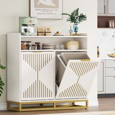 a white cabinet with gold accents in a kitchen next to a potted green plant