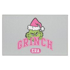 the grinch era door mat is shown in pink and grey with an image of santa's hat on it