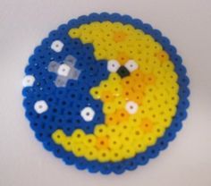 a yellow and blue beaded brooch sitting on top of a white table