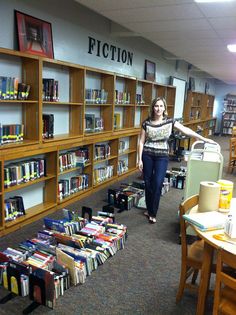 a woman is walking through a library filled with books