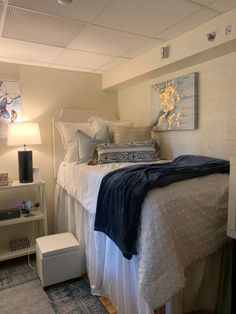 a bed with white sheets and blue blankets on it in a room that has carpeted flooring