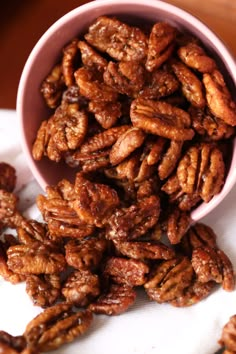 a pink bowl filled with pecans sitting on top of a table