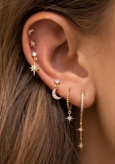 a woman's ear with stars and moon piercings