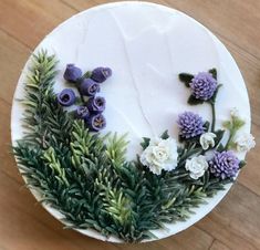 a cake decorated with flowers and greenery on a wooden table