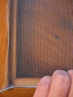 a hand is touching the screen on top of a wooden cabinet with a piece of cloth covering it