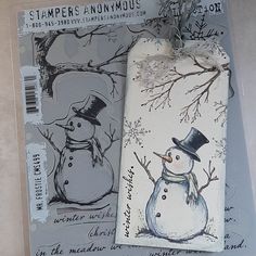 two tags with snowmen on them are attached to the side of a package that is wrapped in plastic