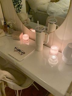 a white desk topped with a mirror next to a table filled with candles and other items