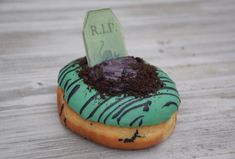 a green frosted donut with dirt on top and a tombstone in the middle