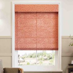 an orange roman blind in a living room with a chair and window behind the blinds