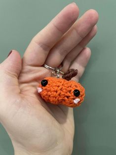 a hand holding a tiny orange crocheted animal keychain