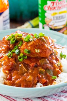 a close up of a plate of food with rice and meat in sauce on the side