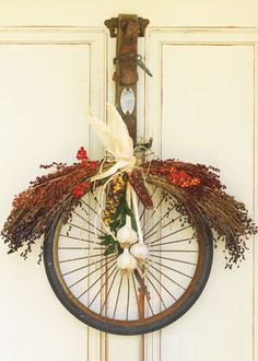 an old bicycle wheel decorated with dried flowers and feathers for fall decor on the wall