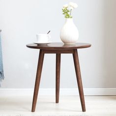 a white vase with flowers on top of a wooden table next to a blue towel