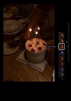 someone is lighting candles on a cake with white frosting and red flowers in the middle